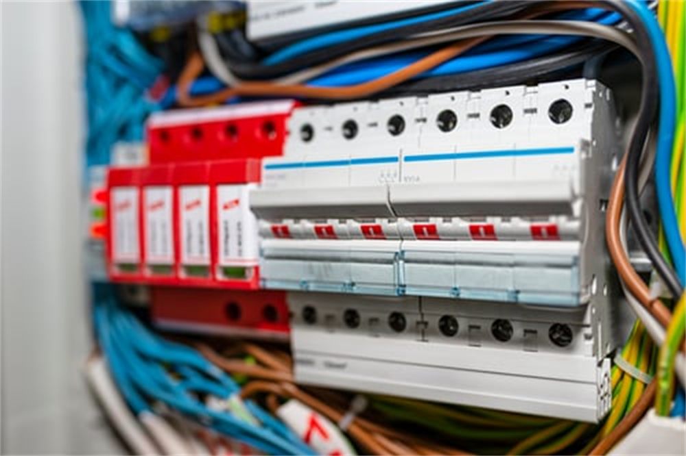 Residential electrical panel with breakers and color-coded circuit wiring in an older Denver, CO home