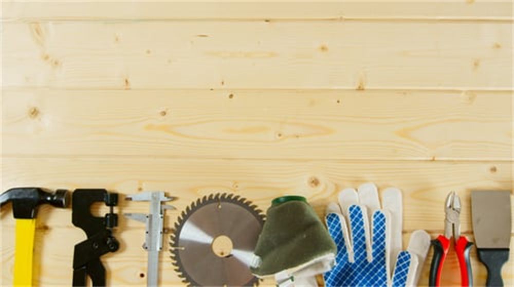 Construction hand tools laid out on a light wood workbench with copy space