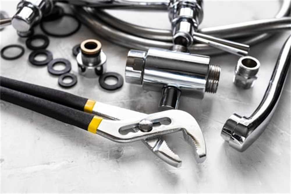 Professional plumbing fittings, supply lines and tongue-and-groove pliers laid out for a residential plumbing job in Denver, CO